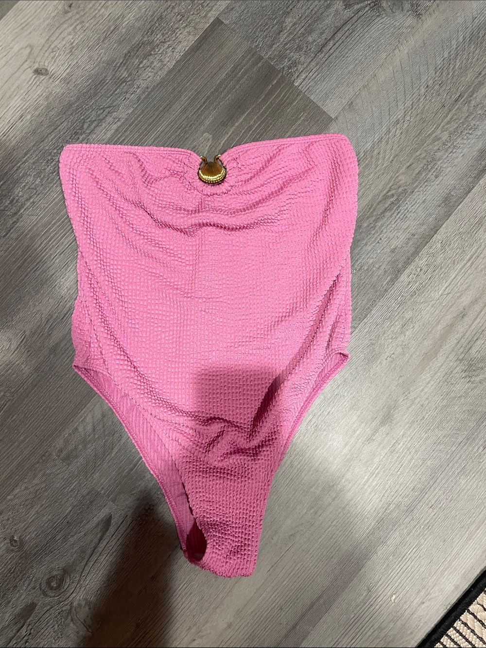Pink strapless one piece swimsuit with gold shell adornment